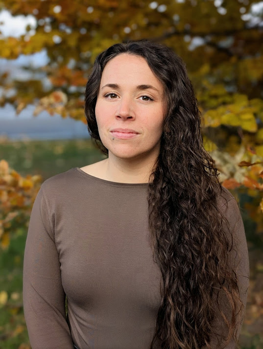 A headshot of Laura Glover, who is a white woman in a light brown top in front of a tree. 